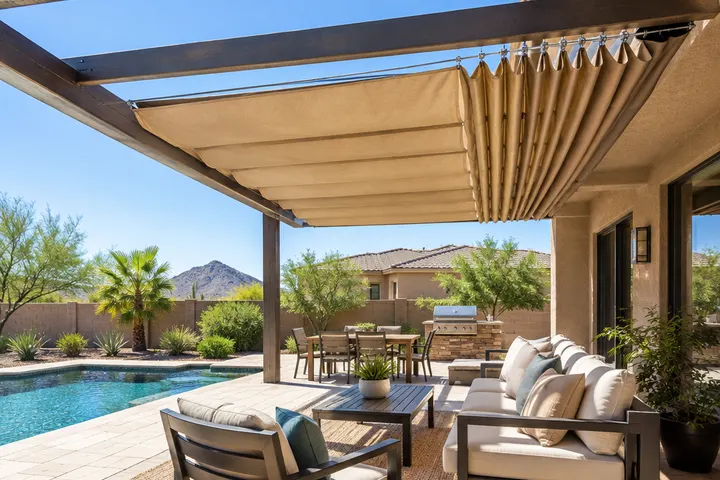 Retractable tan fabric shade canopy gathered on cables across pergola rafters, partly pulled closed, sunny Phoenix backyard